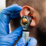 Gros plan d'un médecin utilisant un otoscope pour examiner l'oreille d'un patient.