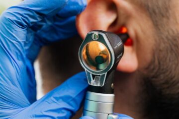 Gros plan d'un médecin utilisant un otoscope pour examiner l'oreille d'un patient.
