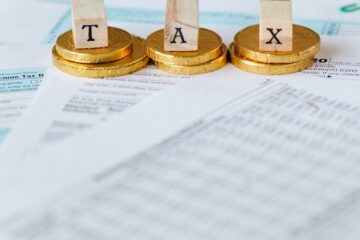 Image mise en scène de pièces d'or avec des tuiles de lettres fiscales sur des documents.