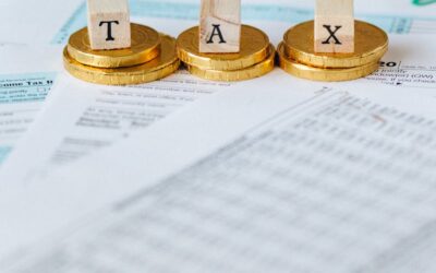 Image mise en scène de pièces d'or avec des tuiles de lettres fiscales sur des documents.